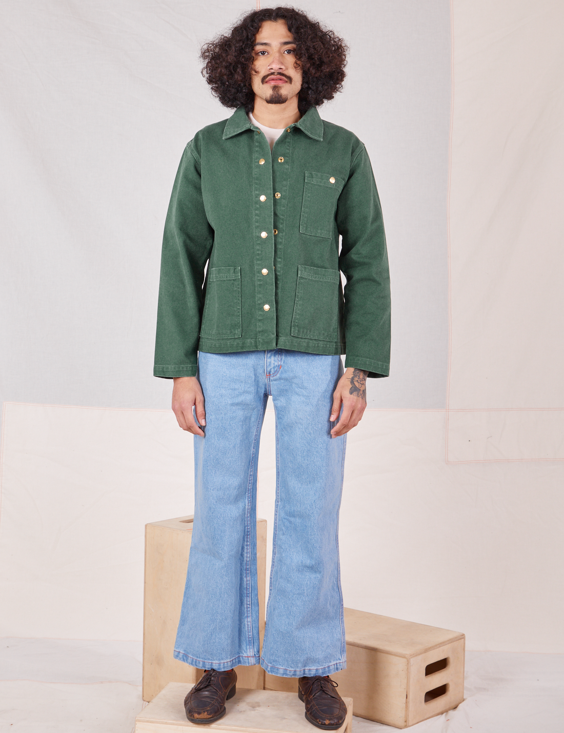 Jesse is wearing Denim Work Jacket in Dark Green Emerald and light wash Sailor jeans