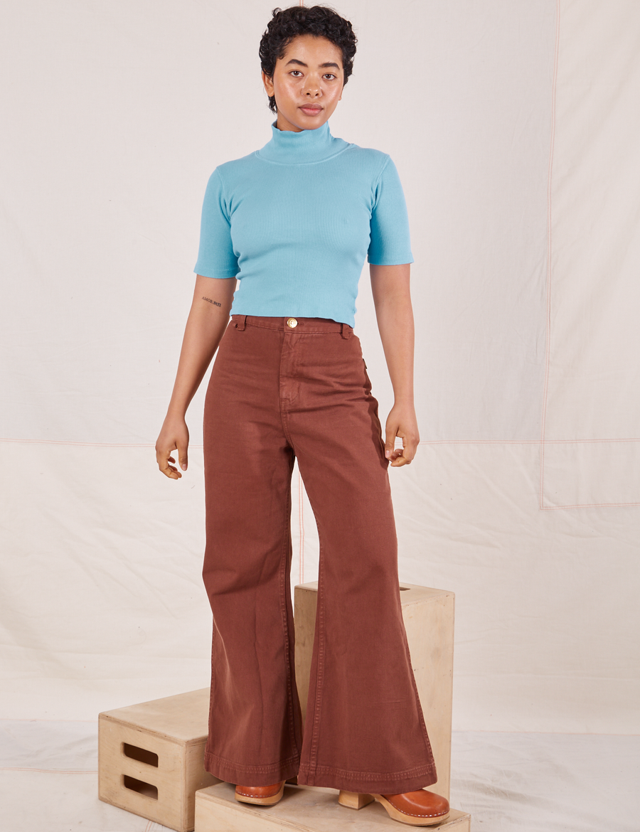 Mika is wearing size P 1/2 Sleeve Essential Turtleneck in Baby Blue paired with fudgesicle brown Bell Bottoms