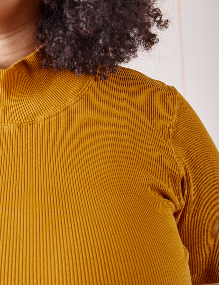 Front shoulder close up of 1/2 Sleeve Essential Turtleneck in Spicy Mustard on Lana