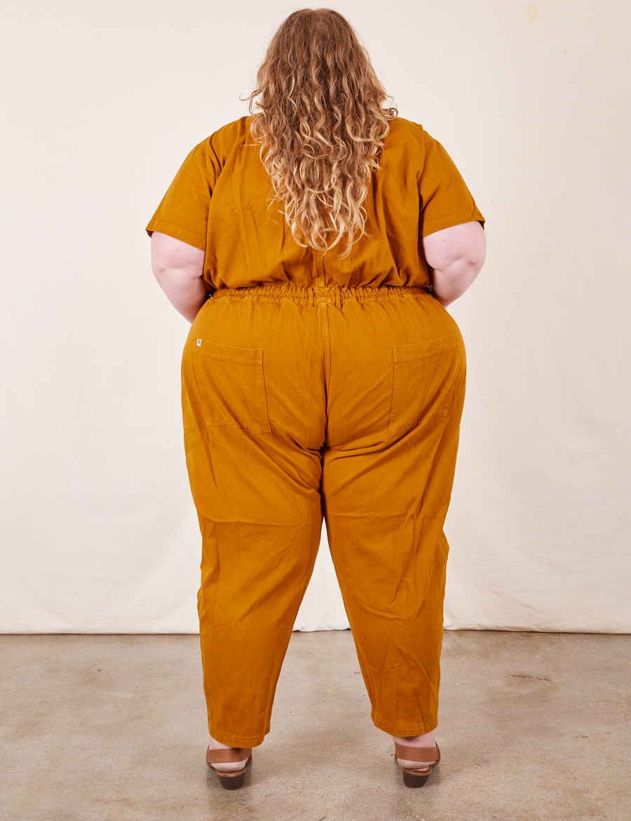 Back view of Short Sleeve Jumpsuit in Spicy Mustard worn by Catie