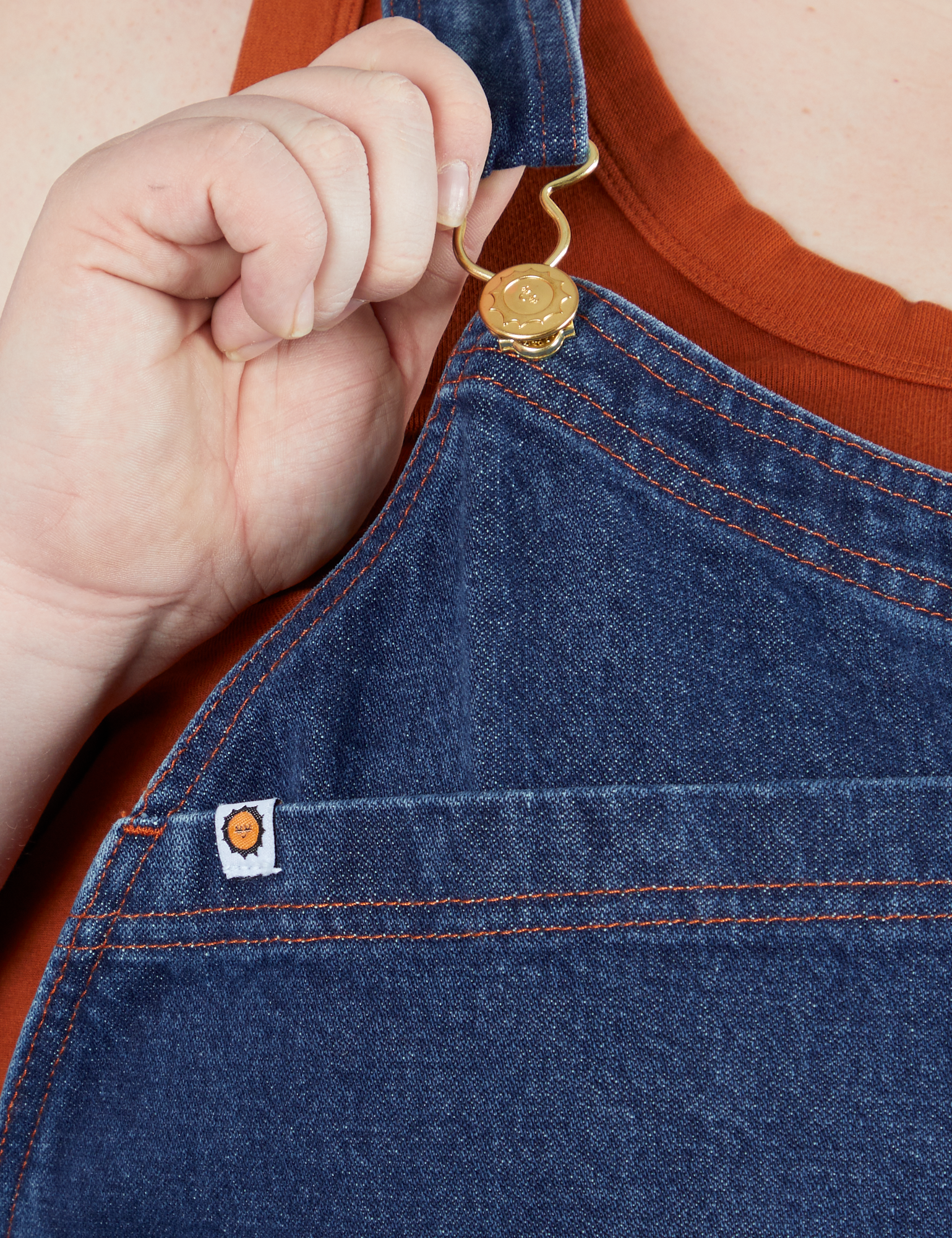 Indigo Denim Original Overalls in Dark Wash front close up with Catie holding onto strap