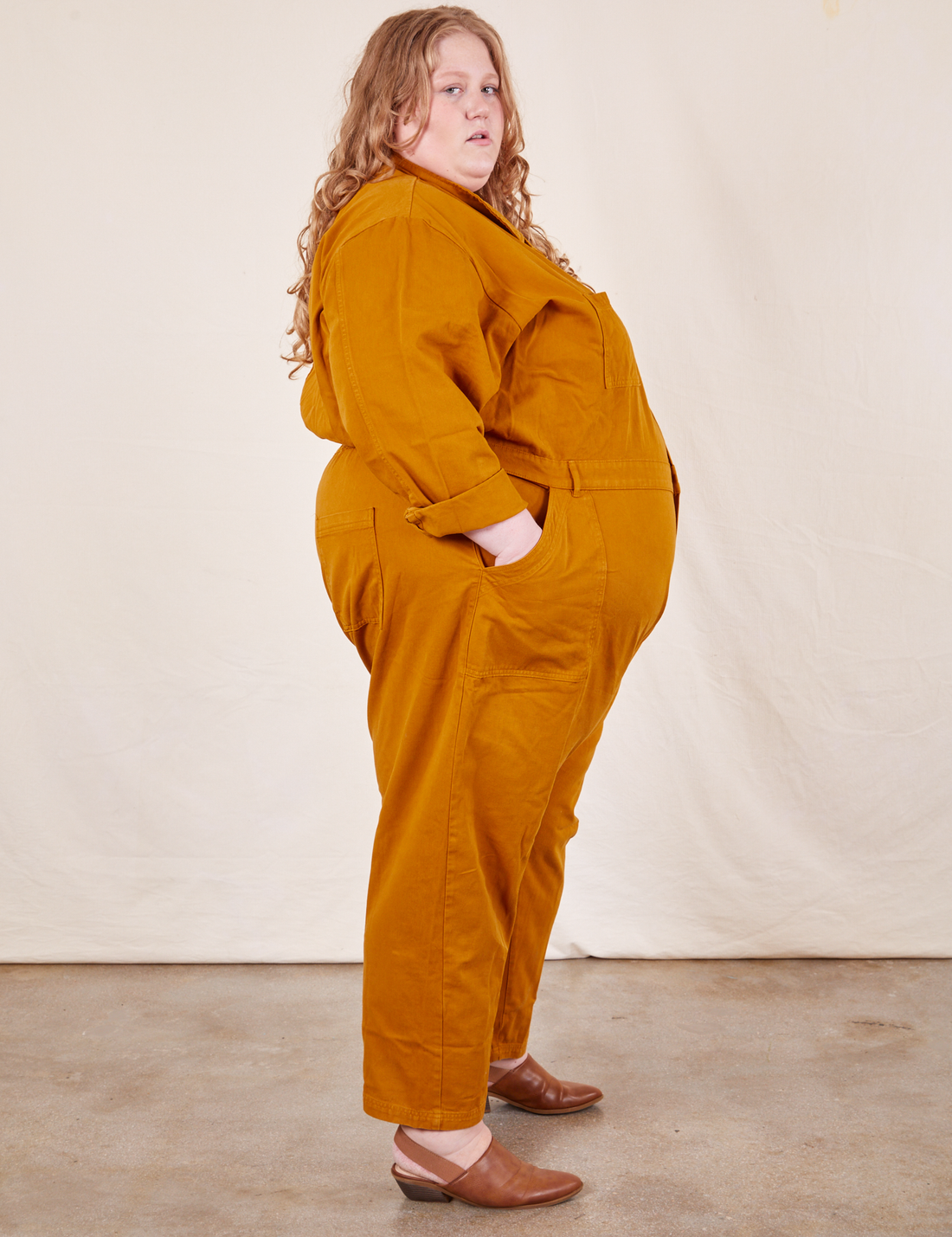 Side view of Everyday Jumpsuit in Spicy Mustard worn by Catie