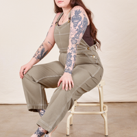 Sydney is sitting on a stool wearing Original Overalls in Khaki Grey