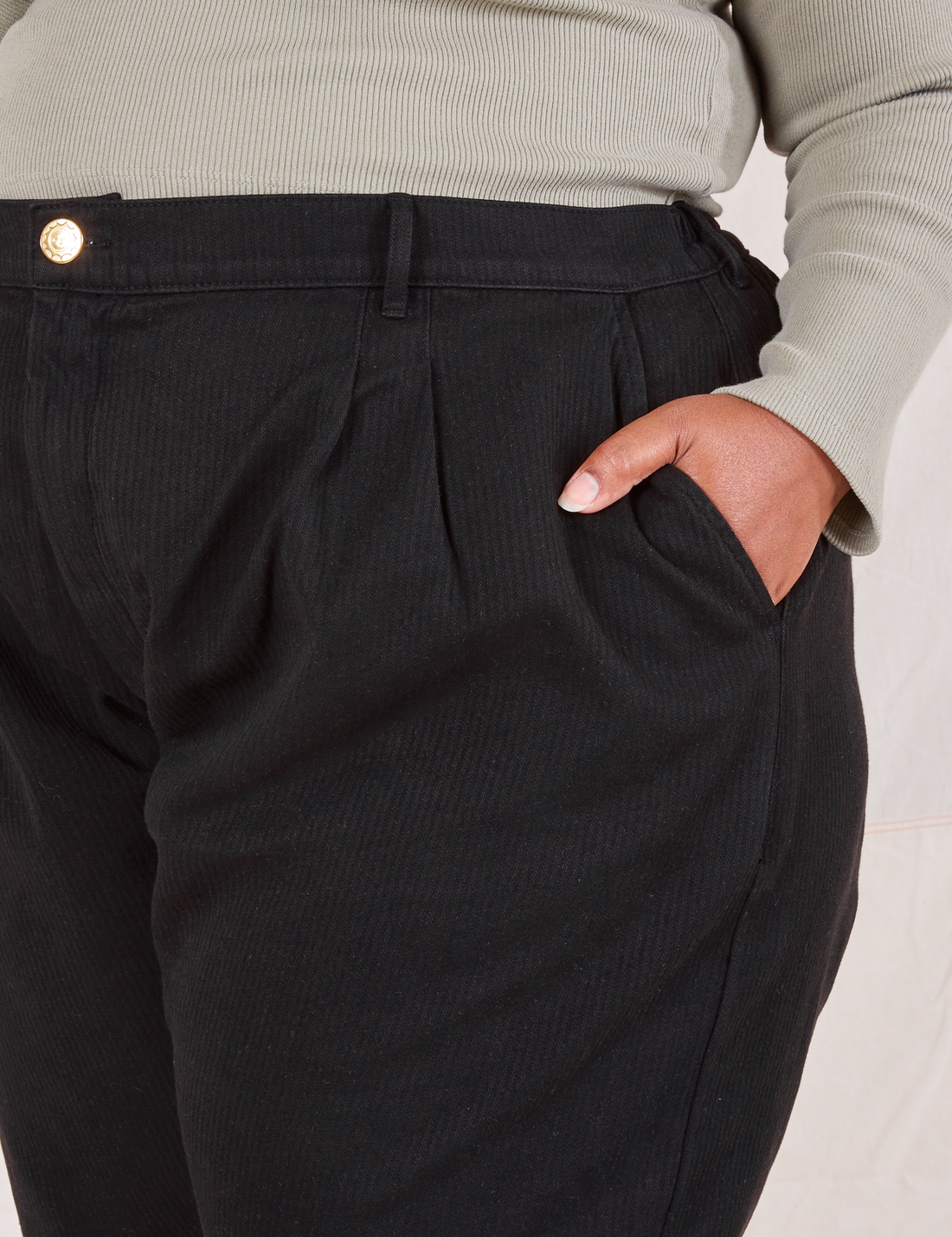 Front pocket close up of Heritage Trousers in Basic Black. Morgan has her hand in the pocket.