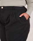 Front pocket close up of Heritage Trousers in Basic Black. Morgan has her hand in the pocket.