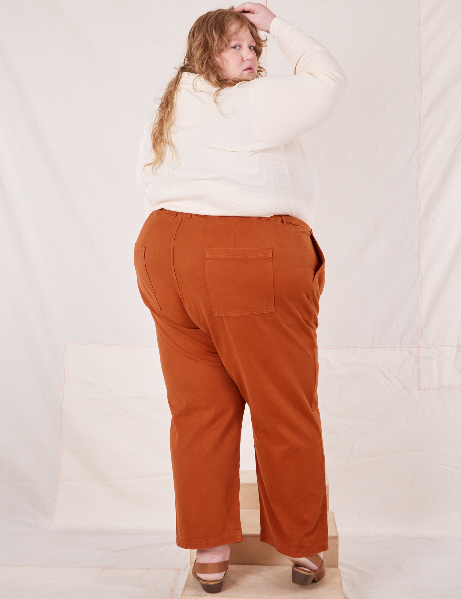 Angled back view of Organic Work Pants in Burnt Terracotta worn by Catie
