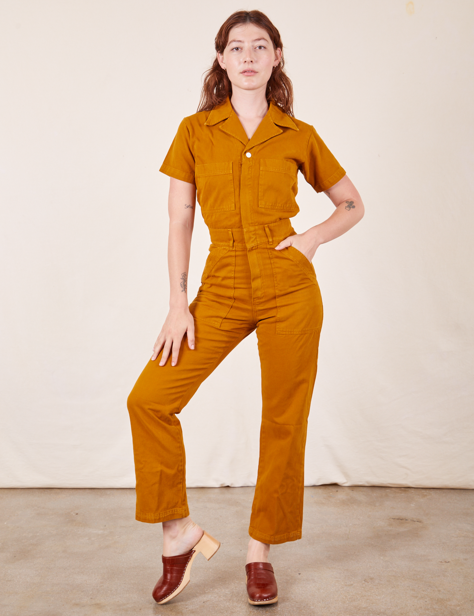 Alex is 5&#39;8&quot; and wearing XS Short Sleeve Jumpsuit in Spicy Mustard