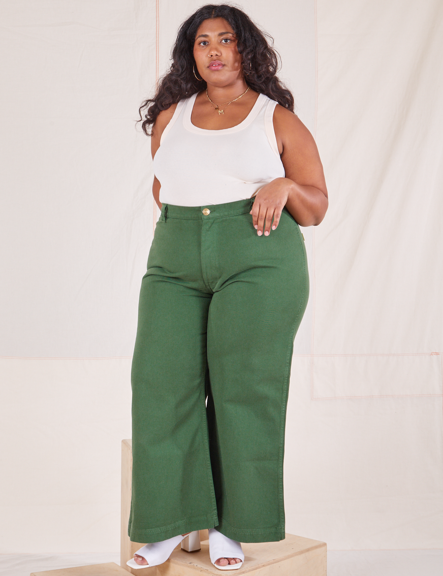 Morgan is 5'5" and wearing 1XL Bell Bottoms in Dark Emerald Green paired with vintage off-white Tank Top