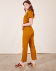 Side view of Short Sleeve Jumpsuit in Spicy Mustard worn by Alex