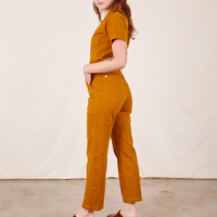 Side view of Short Sleeve Jumpsuit in Spicy Mustard worn by Alex