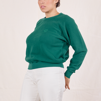 Side view of Heavyweight Crew in Hunter Green and vintage off-white Western Pants worn by Tiara