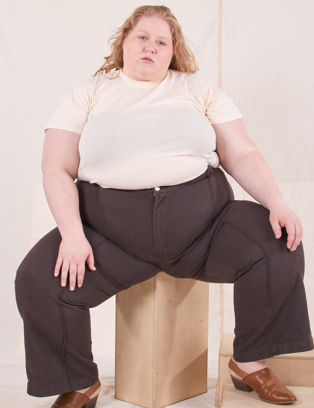 The Organic Vintage Tee in Vintage Off White on Catie wearing espresso brown Western Pants sitting on wooden crate