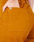 Short Sleeve Jumpsuit in Spicy Mustard back pocket close up on Alex