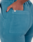 Back pocket close up of Organic Work Pants in Marine Blue. Reece has her hand in the pocket.