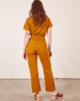 Back view of Short Sleeve Jumpsuit in Spicy Mustard worn by Alex