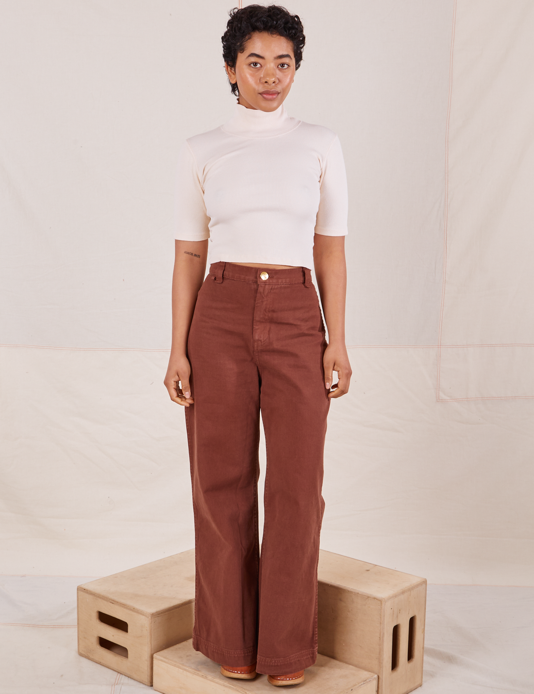 Mika is wearing size P 1/2 Sleeve Essential Turtleneck in Vintage Off White paired with fudgesicle brown Bell Bottoms