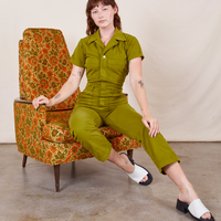 Short Sleeve Jumpsuit in Olive Green on Alex sitting in vintage upholstered chair