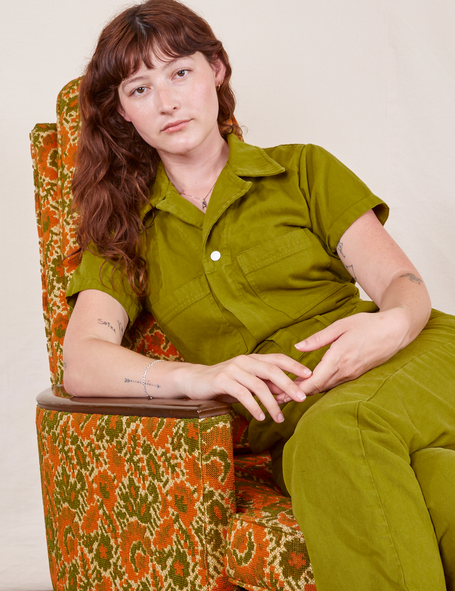 Short Sleeve Jumpsuit in Olive Green on Alex sitting in vintage upholstered chair