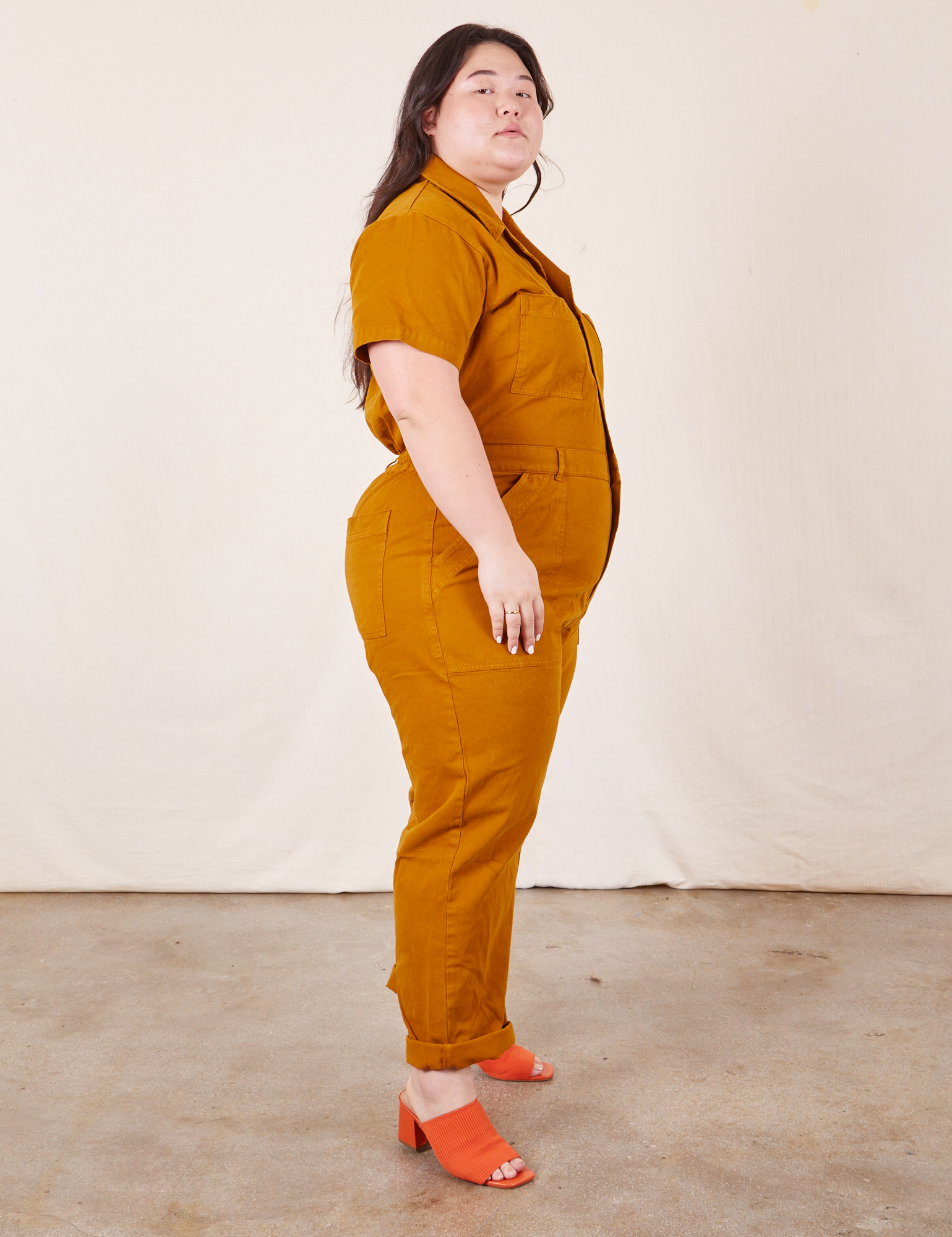 Side view of Short Sleeve Jumpsuit in Spicy Mustard worn by Ashley