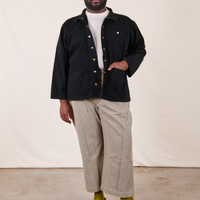 Elijah is 6'4" and wearing 3XL Denim Work Jacket in Basic Black paired with khaki gray Western Pants. He has his right hand in the jacket pocket.