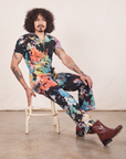 Short Sleeve Jumpsuit in Rainbow Magic Waters on Jesse sitting on vintage stool