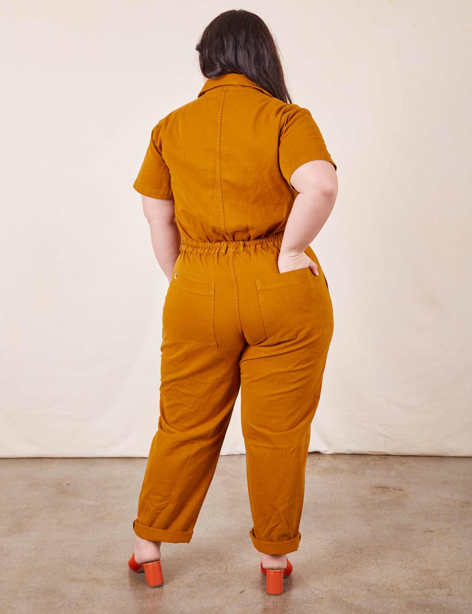 Back view of Short Sleeve Jumpsuit in Spicy Mustard worn by Ashley
