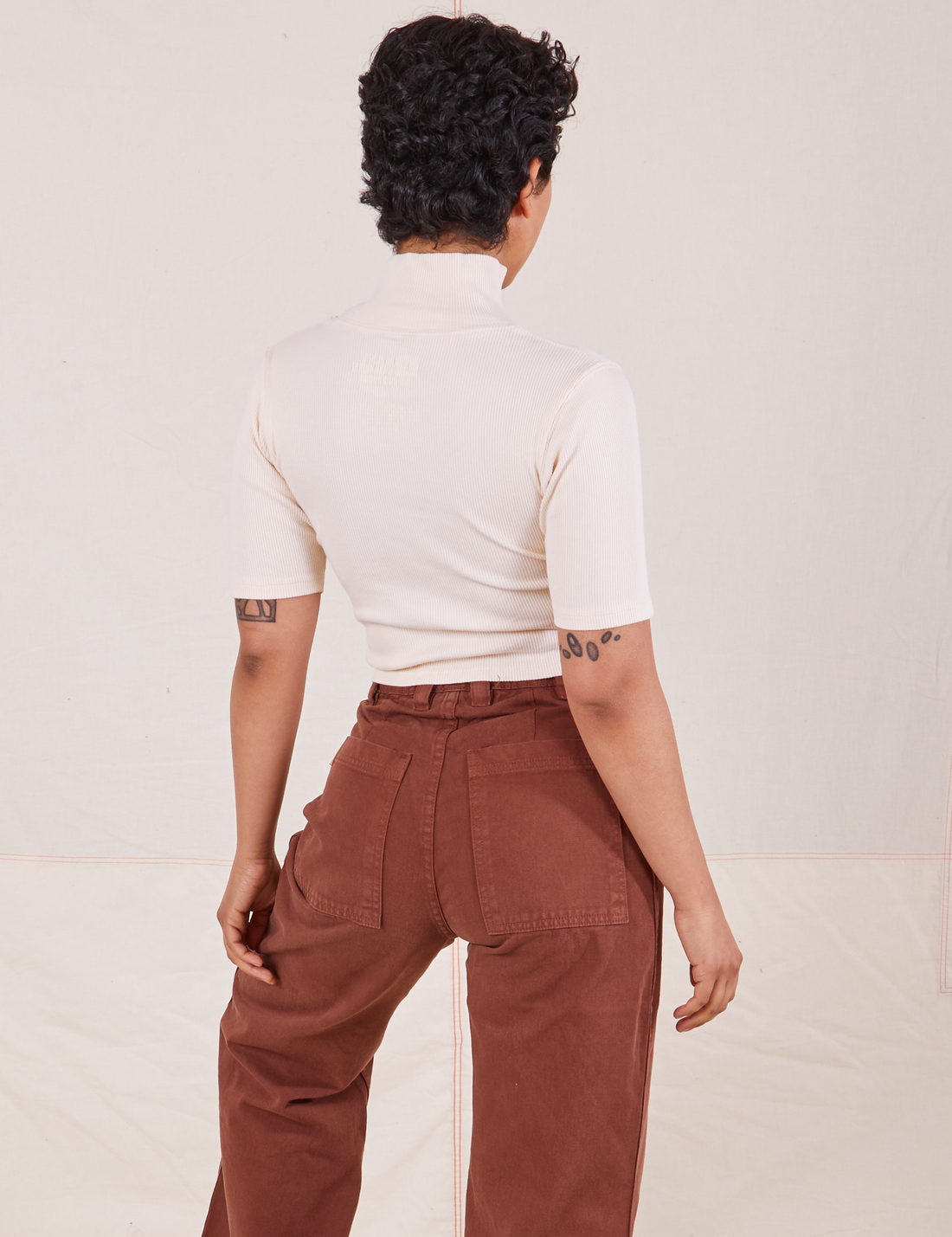 Back view on Mika wearing 1/2 Sleeve Essential Turtleneck in Vintage Off White and fudgesicle brown Bell Bottoms