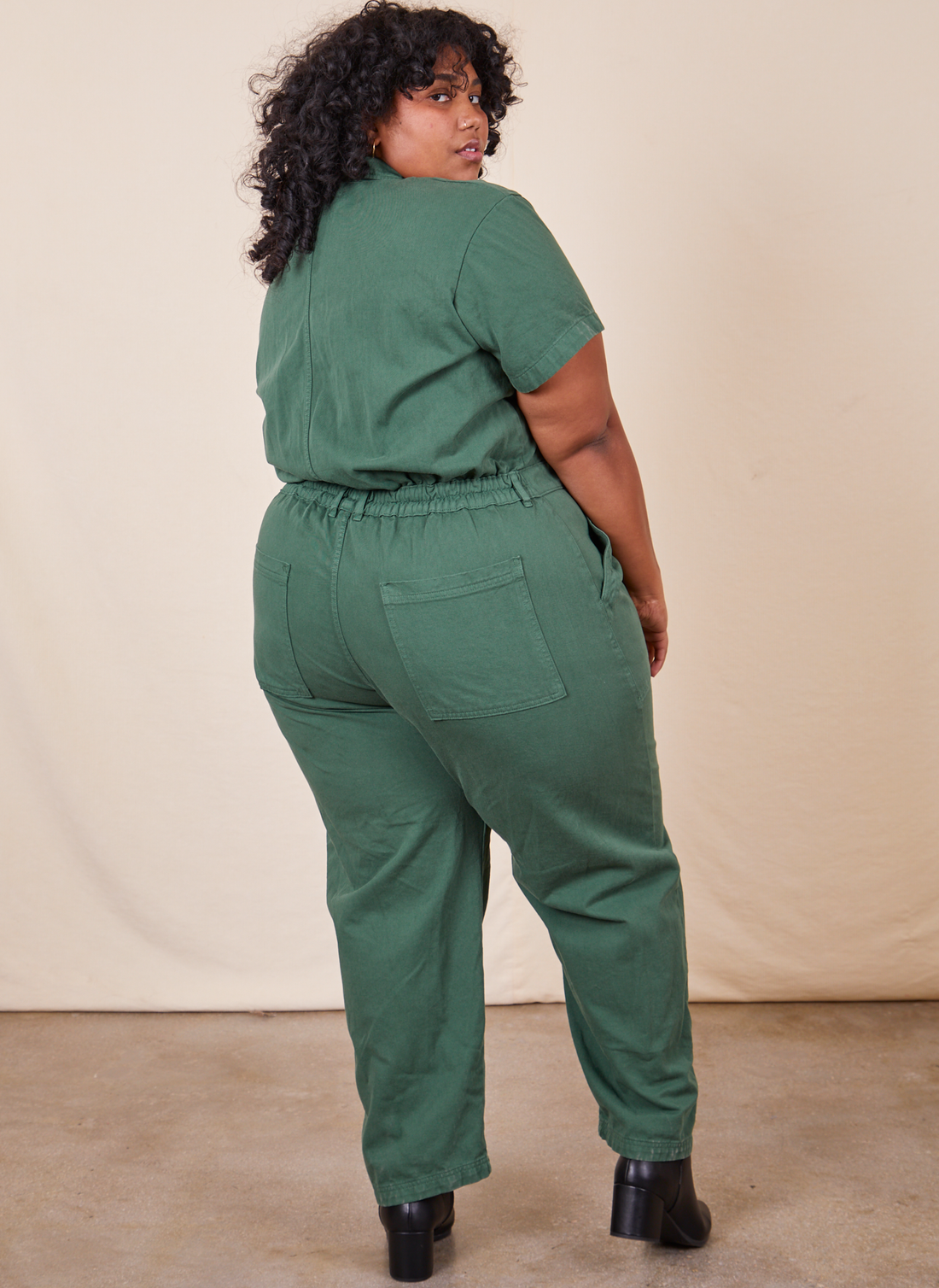 Back view of Short Sleeve Jumpsuit in Dark Emerald Green worn by Morgan