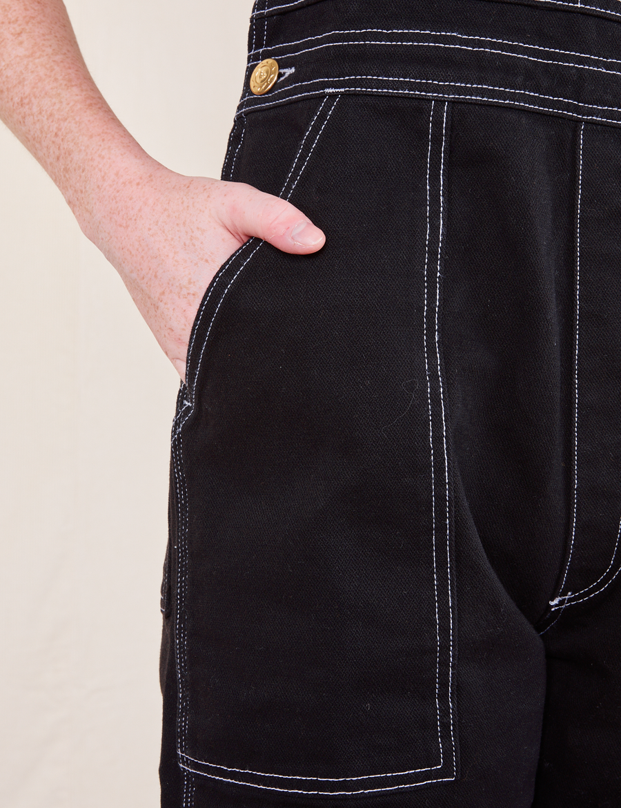 Original Overalls in Basic Black front pocket close up. Margaret has her hand in the pocket.
