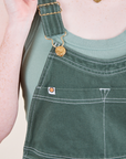 Original Overalls in Dark Emerald Green front close up featuring gold sun baby button