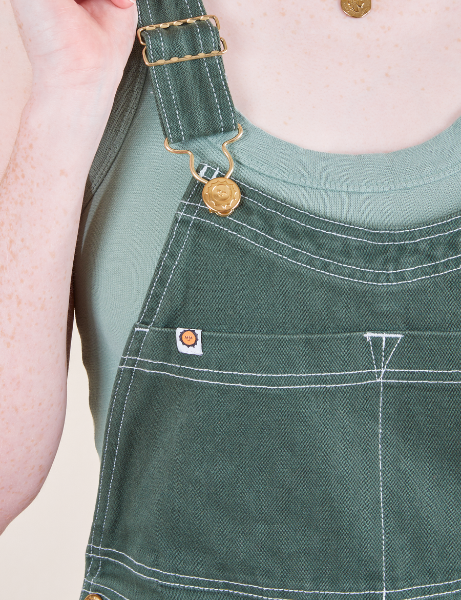 Original Overalls in Dark Emerald Green front close up featuring gold sun baby button