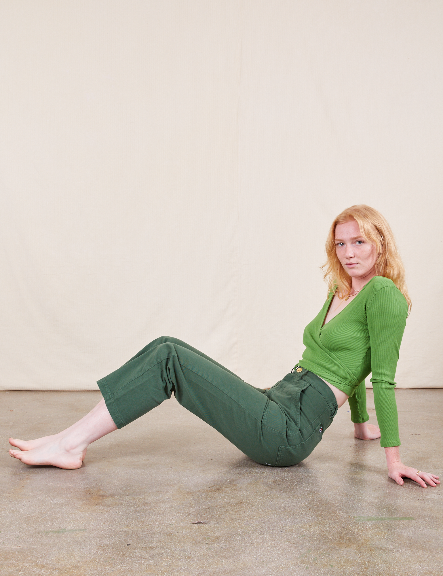 Margaret is wearing Work Pants in Dark Emerald Green and bright olive Wrap Top
