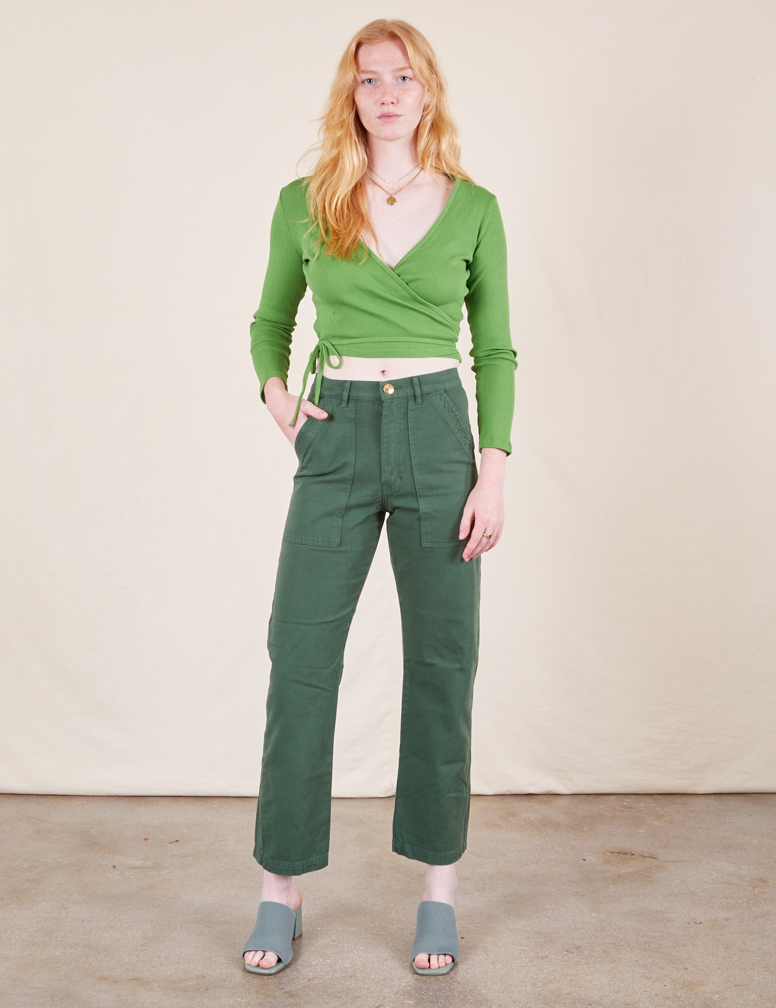 Margaret is 5'11" and wearing XXS Work Pants in Dark Emerald Green paired with bright olive Wrap Top