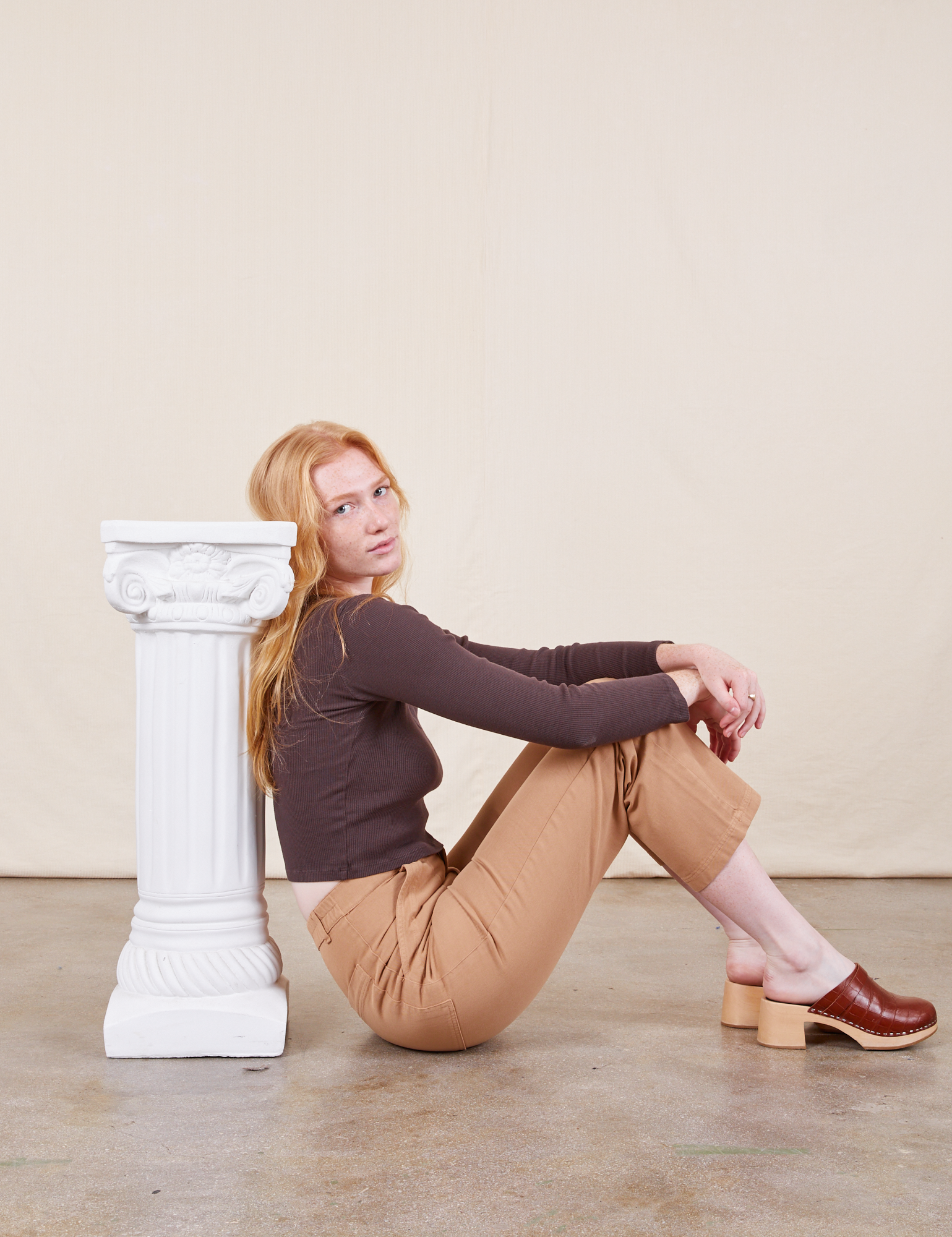 Margaret is sitting on the floor wearing Work Pants in Tan and espresso brown Long Sleeve V-Neck Tee
