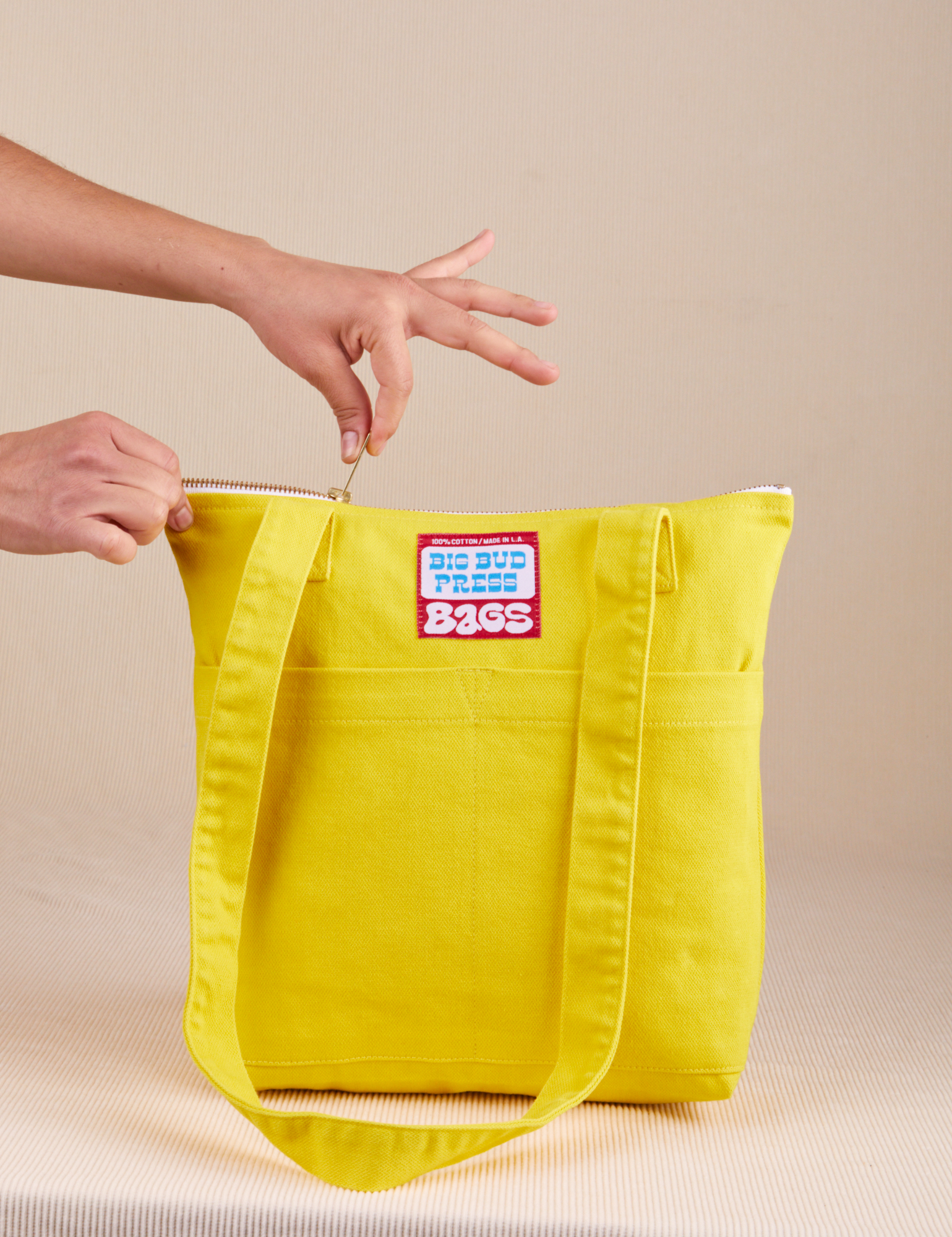 Over-Shoulder Zip Mini Tote in golden yellow being unzipped by model