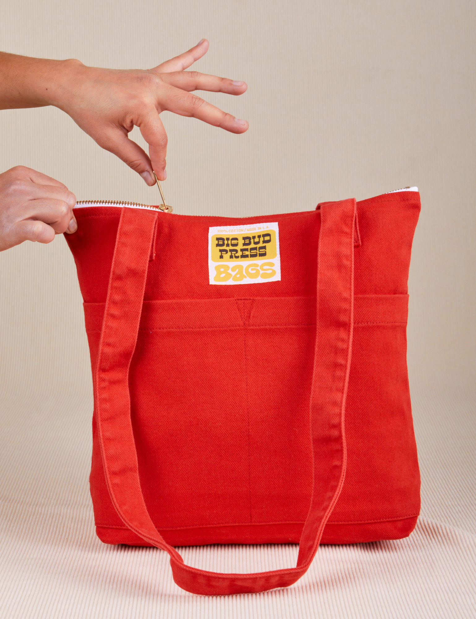 Over-Shoulder Zip Mini Tote in mustang red being unzipped by model