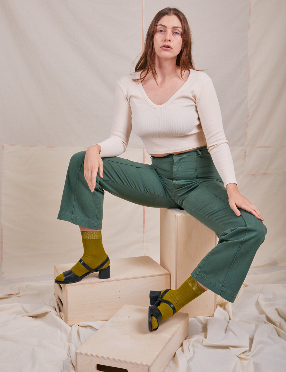 Allison is wearing Long Sleeve V-Neck Tee in Vintage Tee Off-White and dark emerald green Western Pants