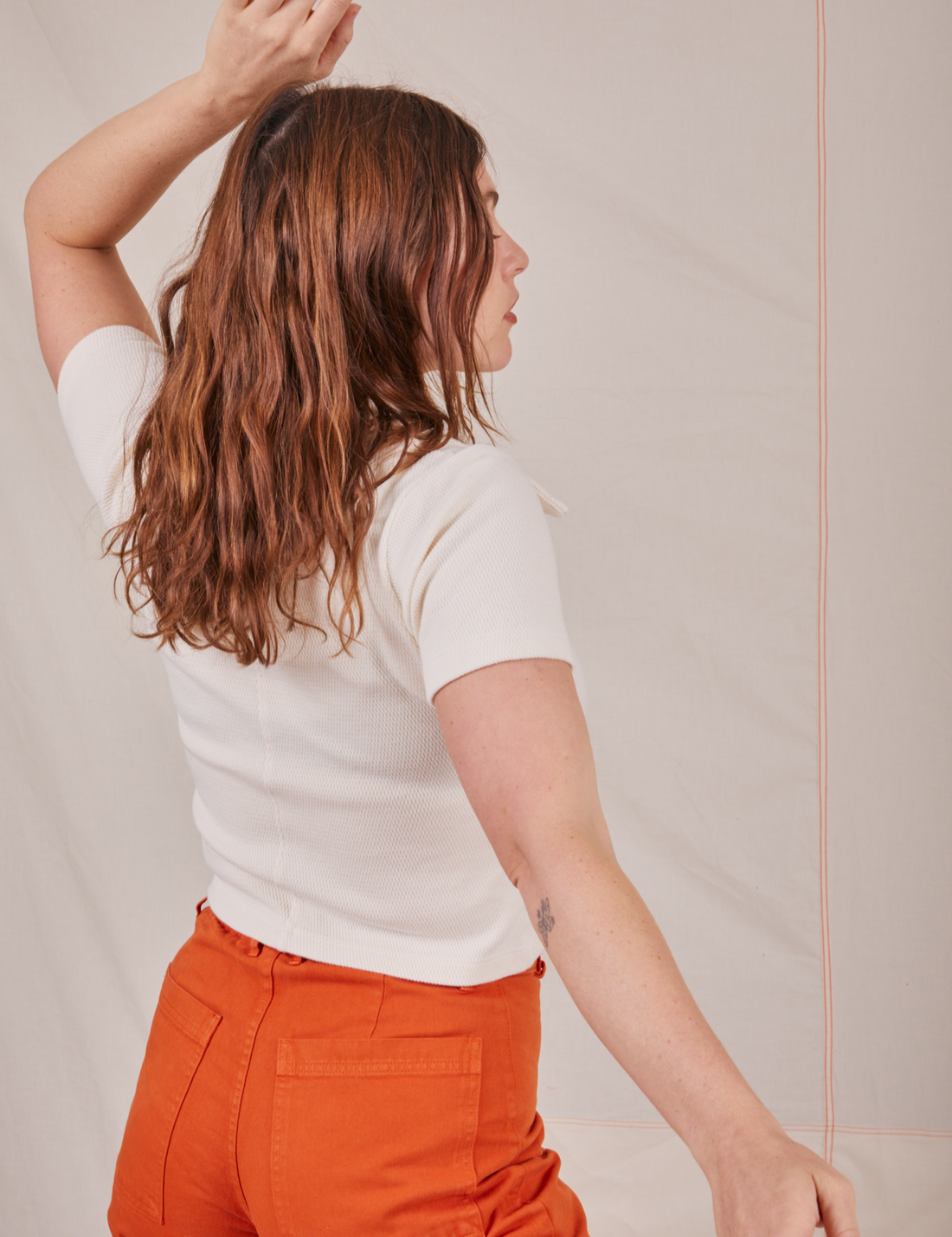 Angled back view of Fisherman Polo in Vintage Tee Off-White worn by Allison