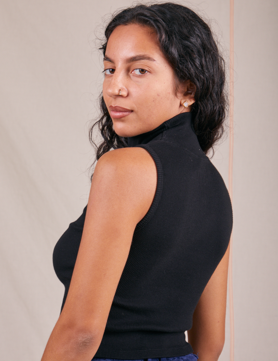 Angled back view of Sleeveless Essential Turtleneck in Basic Black worn by Blair