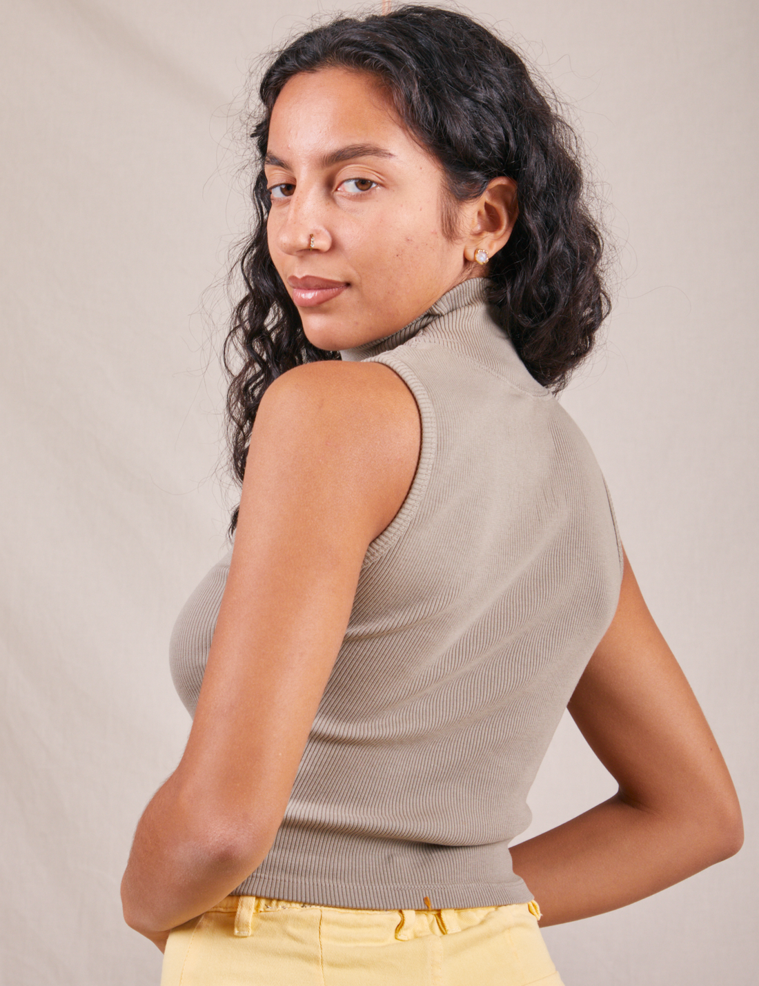 Angled back view of Sleeveless Essential Turtleneck in Khaki Grey worn by Blair