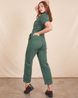 Angled back view of Short Sleeve Jumpsuit in Dark Emerald Green worn by Allison