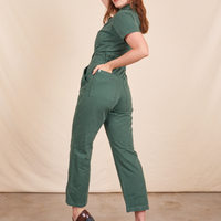 Angled back view of Short Sleeve Jumpsuit in Dark Emerald Green worn by Allison