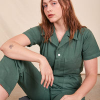 Allison is sitting on the floor and wearing Short Sleeve Jumpsuit in Dark Emerald Green
