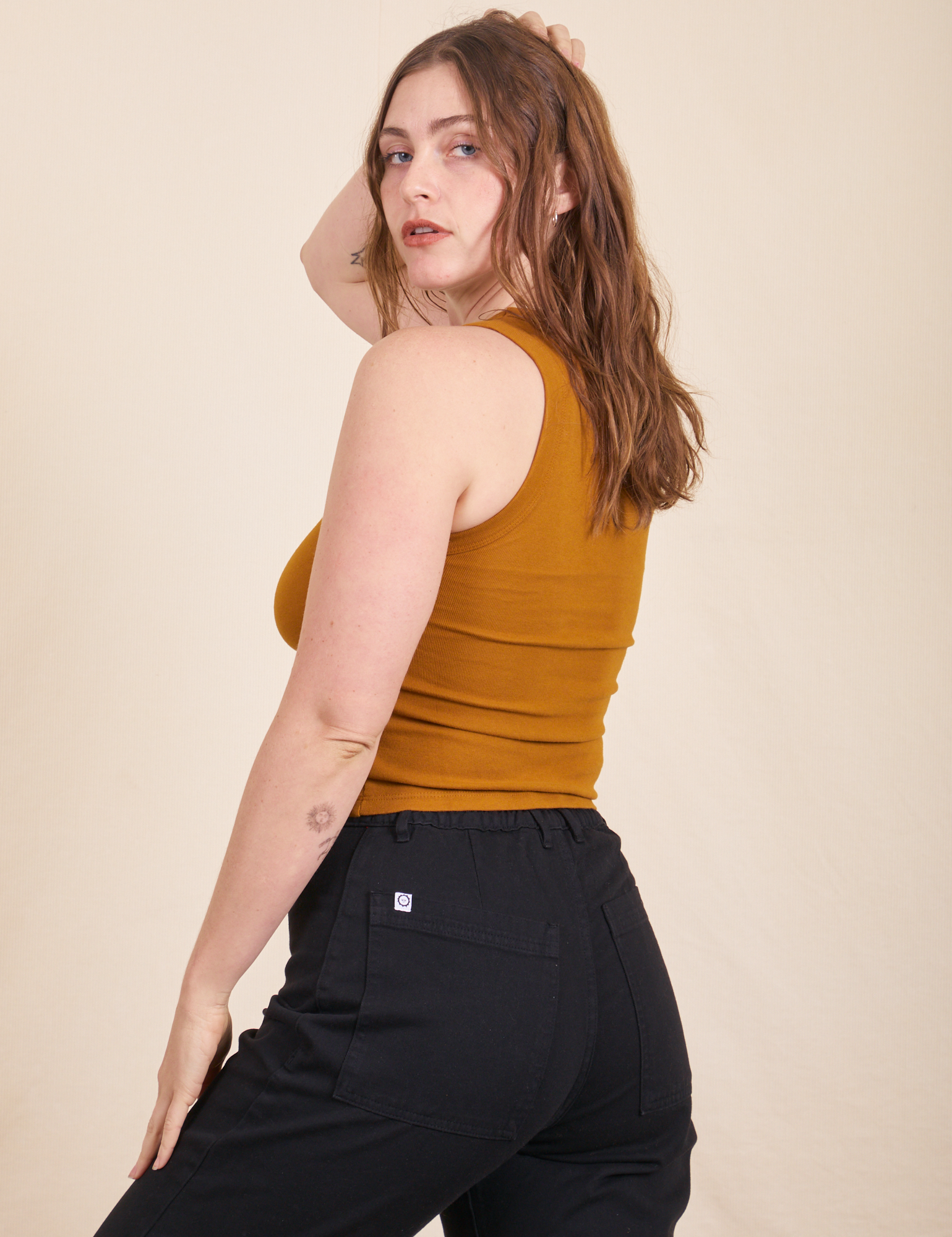 Angled back view of Tank Top in Spicy Mustard and black Western pants on Allison