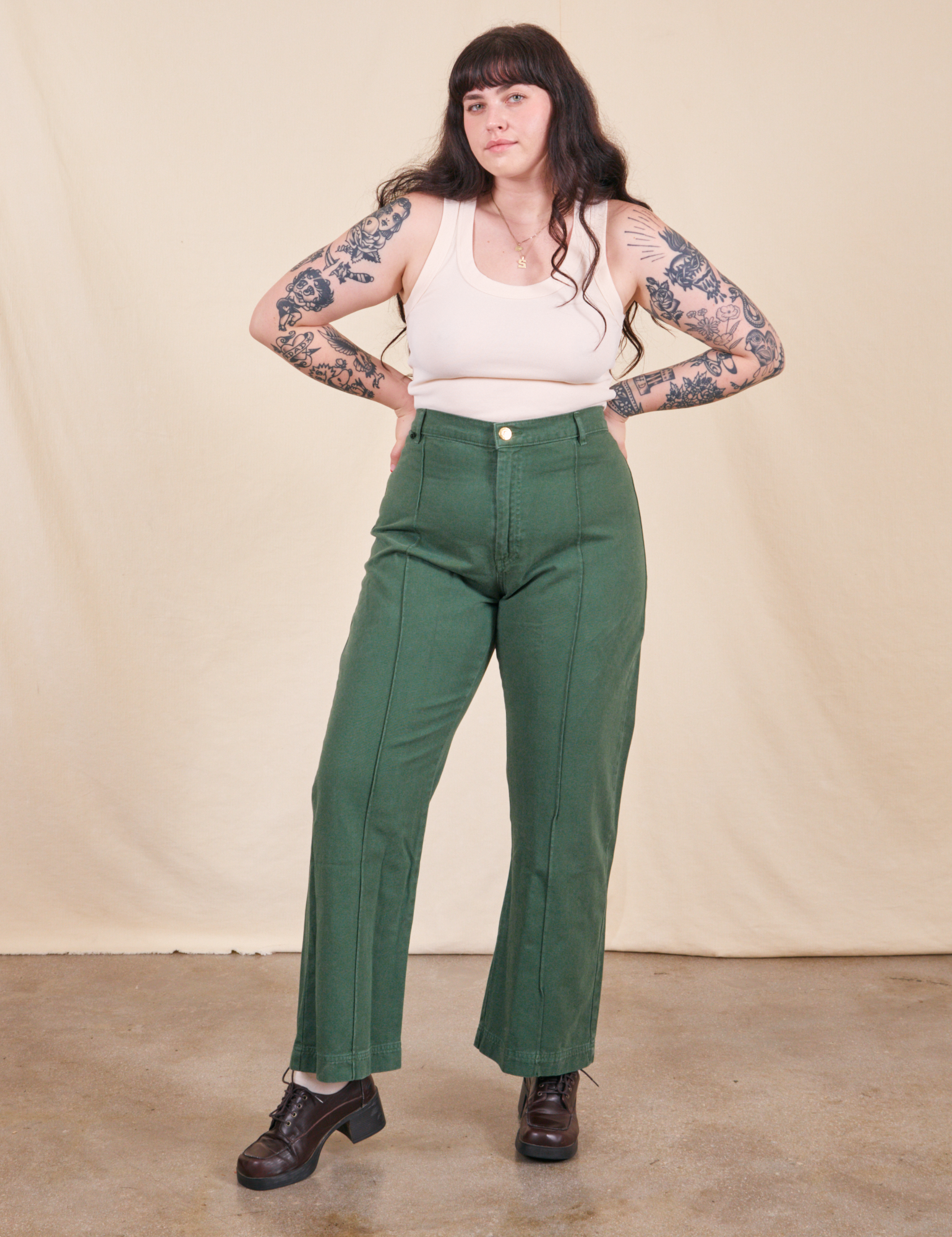 Sydney is 5&#39;9&quot; and wearing M Western Pants in Dark Emerald Green paired with vintage off-white Tank Top